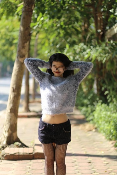 Small Asian girl with eyeglasses Irena posing in her cute outfit outdoors