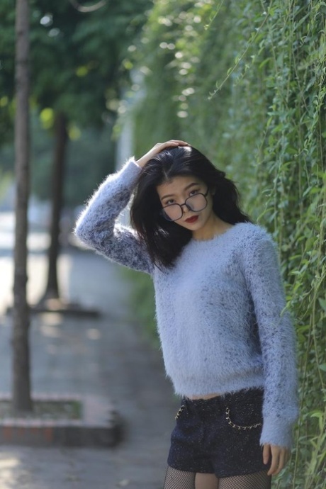 Pretty Asian girl with glasses Irena posing in her sweater and short skirt