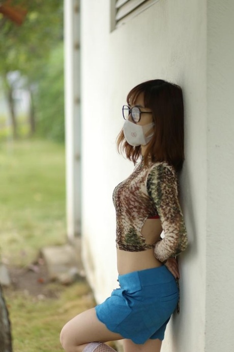 Asian brunette babe with a mask & glasses poses in her sexy outfit