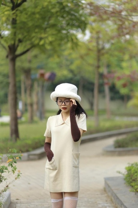 Tiny Asian girl with glasses Irena posing in her elegant white outfit outside