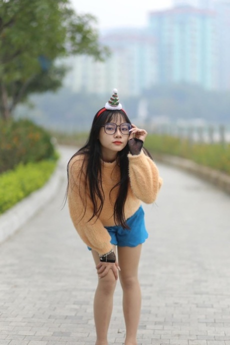 Petite Asian girl with glasses posing in her sweater and denim shorts