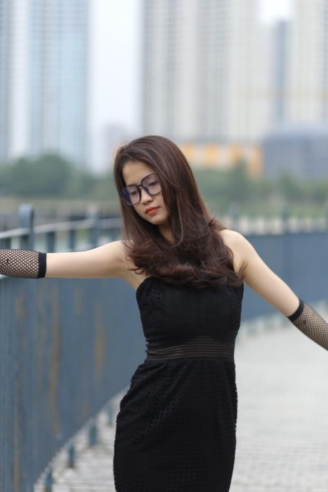 Pretty Asian girl with glasses Maya posing in her long black dress outdoors