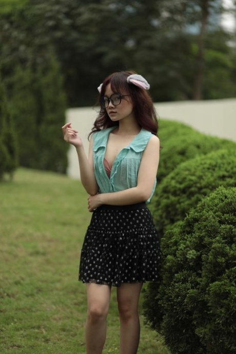 Gorgeous Asian teen with glasses poses in her provocative outfit outside