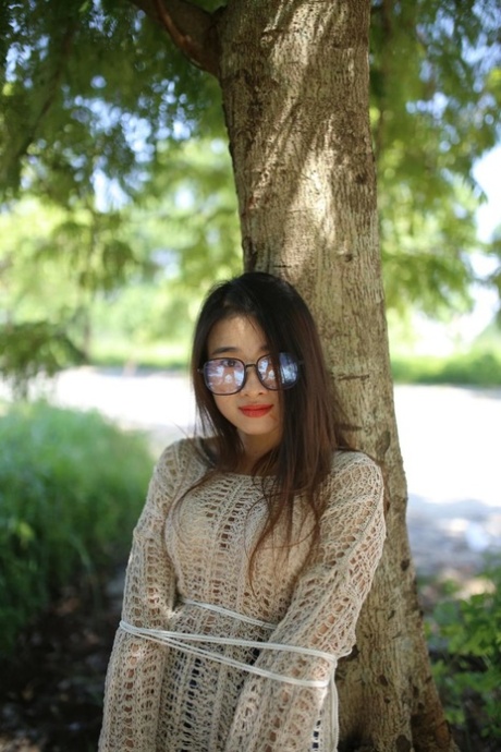 Schönes asiatisches Model mit Brille Elena posiert in ihrem süßen Outfit in der Natur