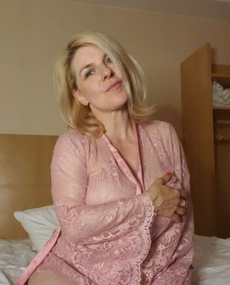 Blond, moden kvinne blottlegger sin store utringning og poserer i sexy rosa undertøy.