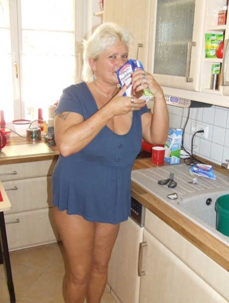 Den fede, blonde bedstemor Katja hælder chokolademælk ud over sine store bryster i badekarret