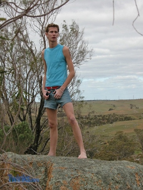 Blonde twink doet zijn rode zwembroek uit en pronkt met zijn harige lul buiten