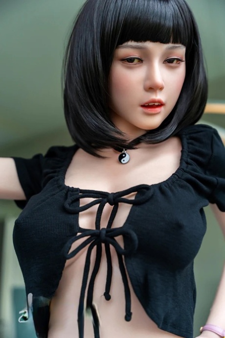 Dark-haired silicone sex doll Coco teasing with her boobs in a solo