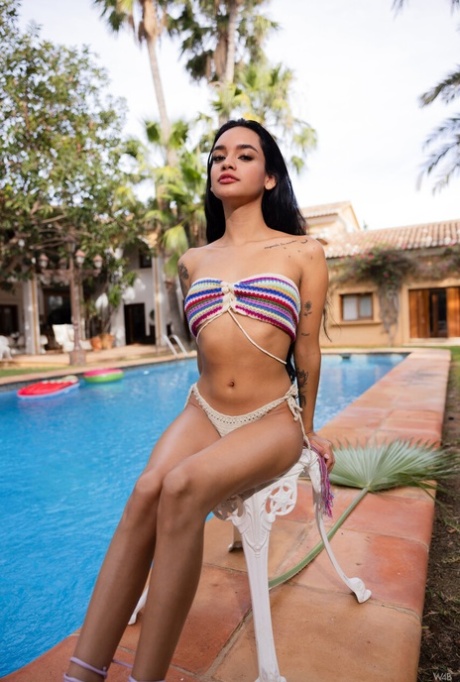 Slim Latina teen Dulce slowly undresses and poses nude poolside